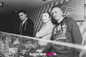 tomislav 2 DJ Tomislav (Tom Black) stoji nasmiješen ispred DJ pulta na vjenčanju, u pozadini su reflektori i plesni podij.